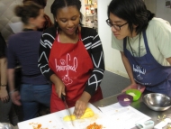 A volunteer helping a student chop